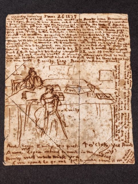 A brown piece of paper with handwriting and a sketch of two women sat at a table writing.