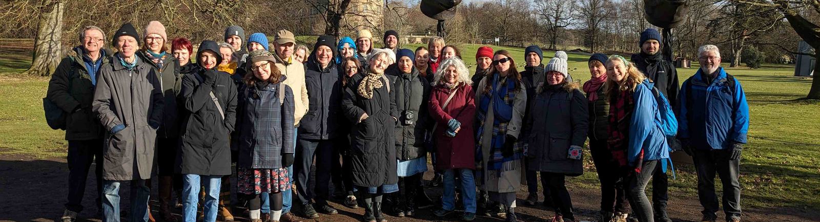 Photo of a large group of people, outside on a bright day, looking to the camera.