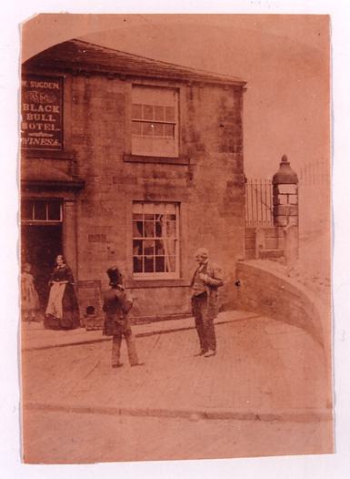 Black and white photo of two Victorian men and two Victorian women standing outside a public house.