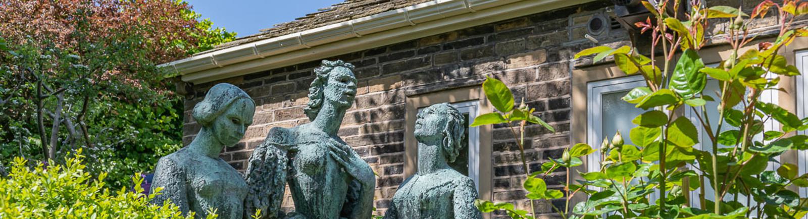 Photo of a statue in a garden of three women.