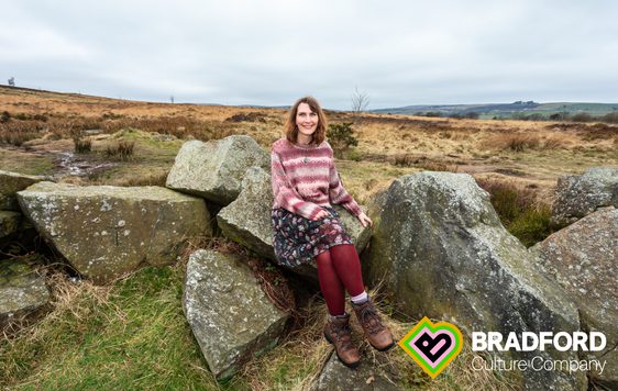 A woman sitting on a rock, surrounded by moorland.