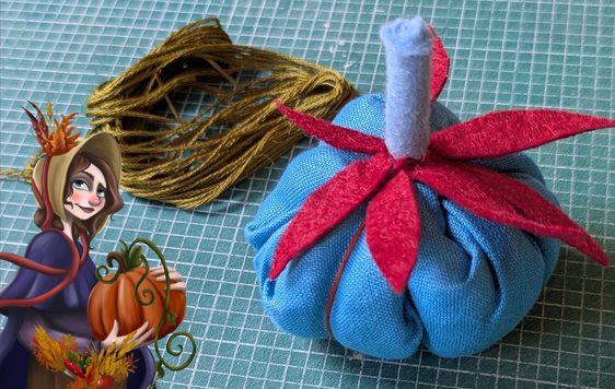 Photo of a fabric pumpkin with an illustration of a woman holing a pumpkin in bottom left corner.