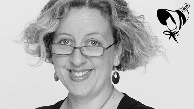 Black and white image of a woman wearing glasses and smiling.
