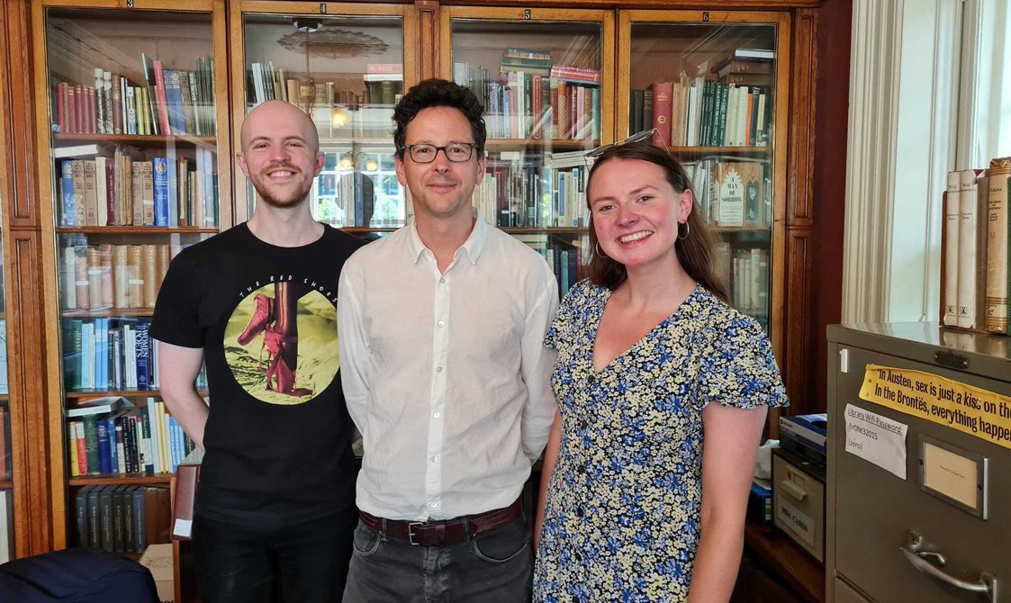 Three people stood together in a library.