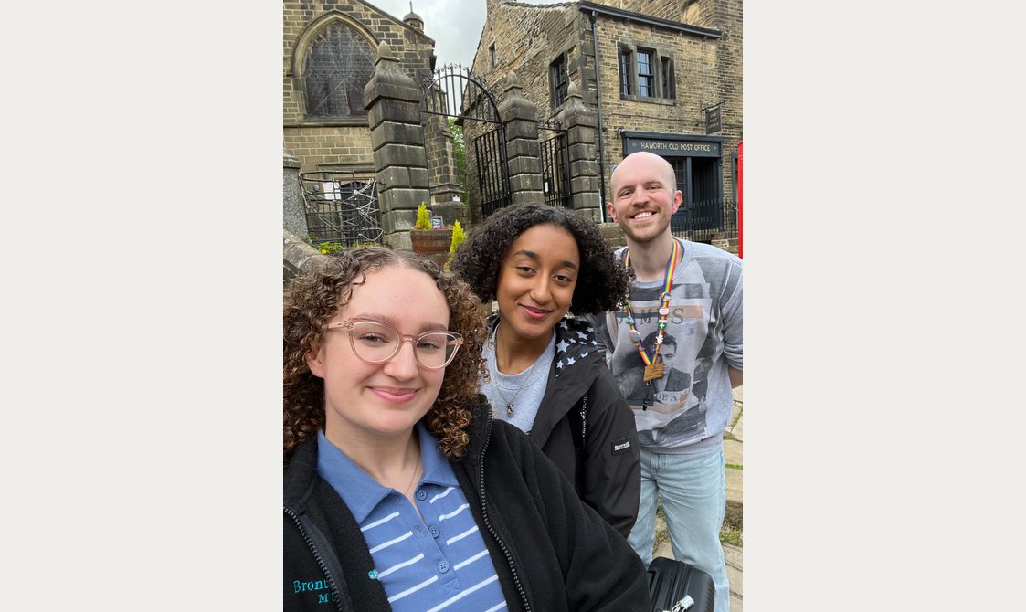 The people standing together in front of stone buildings.