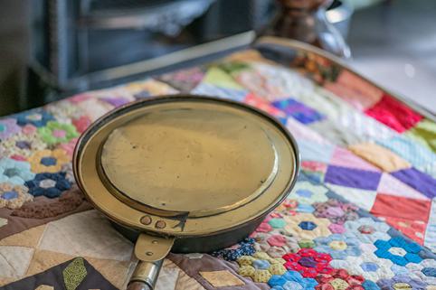 Photo of a metal bed pan on a colourful quilt.