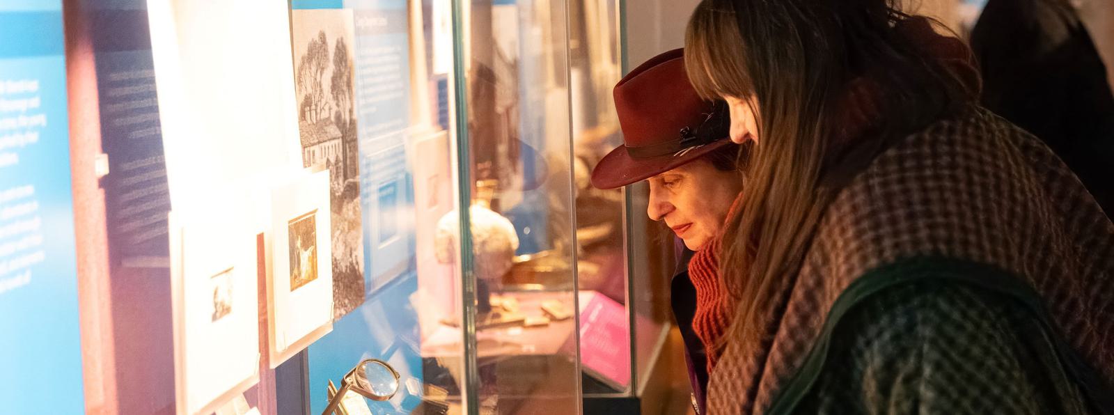 Photo of two women looking at a lit-up museum display case.