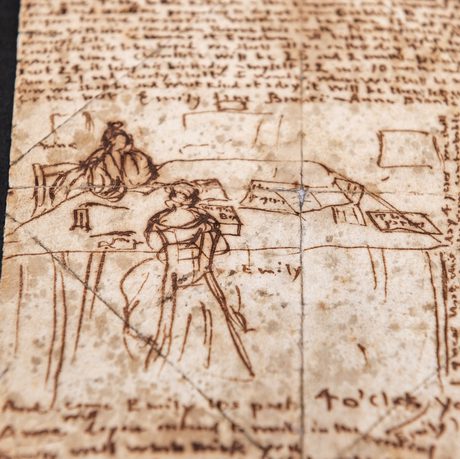 Photo of a yellowed piece of paper, including dark handwriting and a sketch of two figures sitting at a desk.