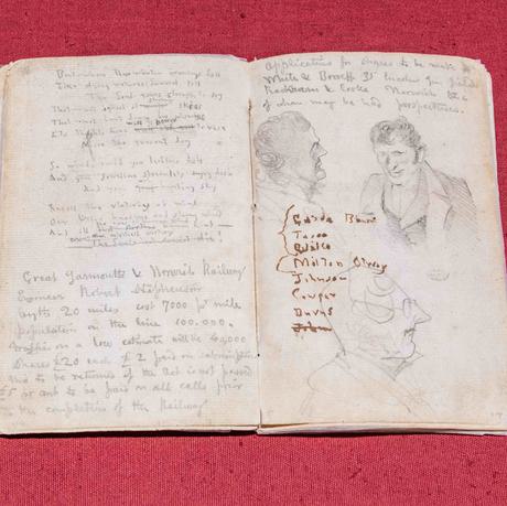 Photo of a yellowed notebook with writing and sketches on its pages.