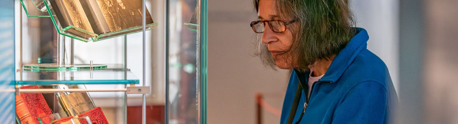 Photo of a visitor looking at books in a glass case.
