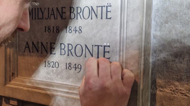 Photo of a man working on a stone carved memorial.