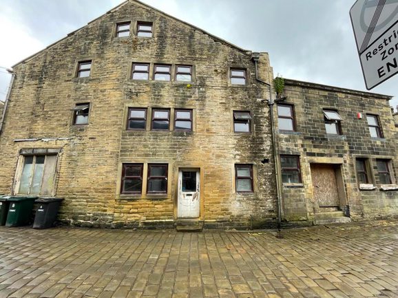 Photo of a large building with lots of small windows on a cobbled street.