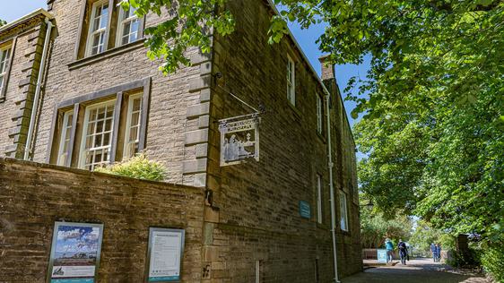 Photo of the side of a Victorian building with trees bordering the frame.