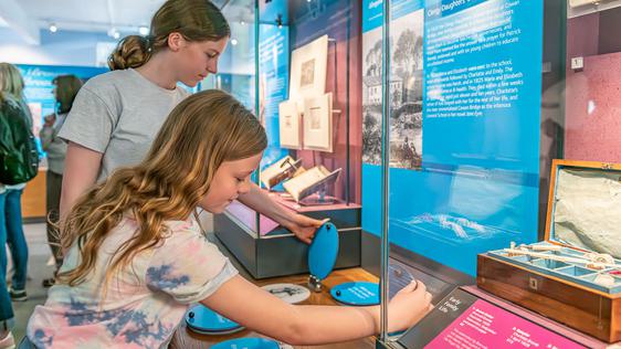 Photo of two young teenage girls looking at a museum display.