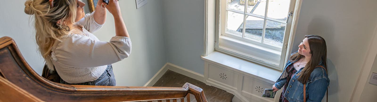 Photo of two young women taking a photo in the stairway of the Bronte Parsonage.