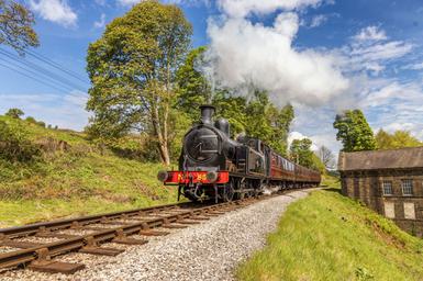 Photo of a steam train going through green countryside.